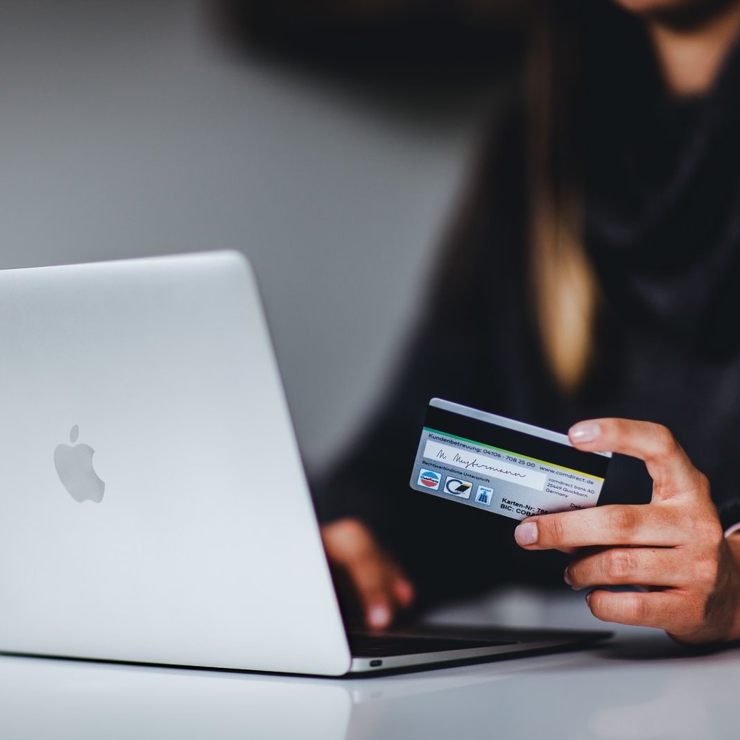 woman holding black smartphone near silver macbook